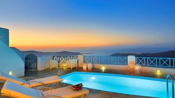 Relax on the rooftop terrace with a pool, lounge chairs, and a table, taking in the stunning coastline and hill views.