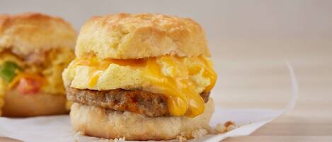A breakfast sandwich with a biscuit bun, egg, cheese, and a meat patty.