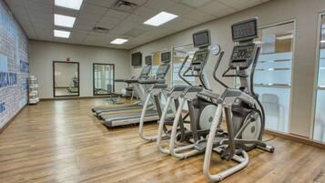 A gym with treadmills, stationary bikes, and a mirrored wall.