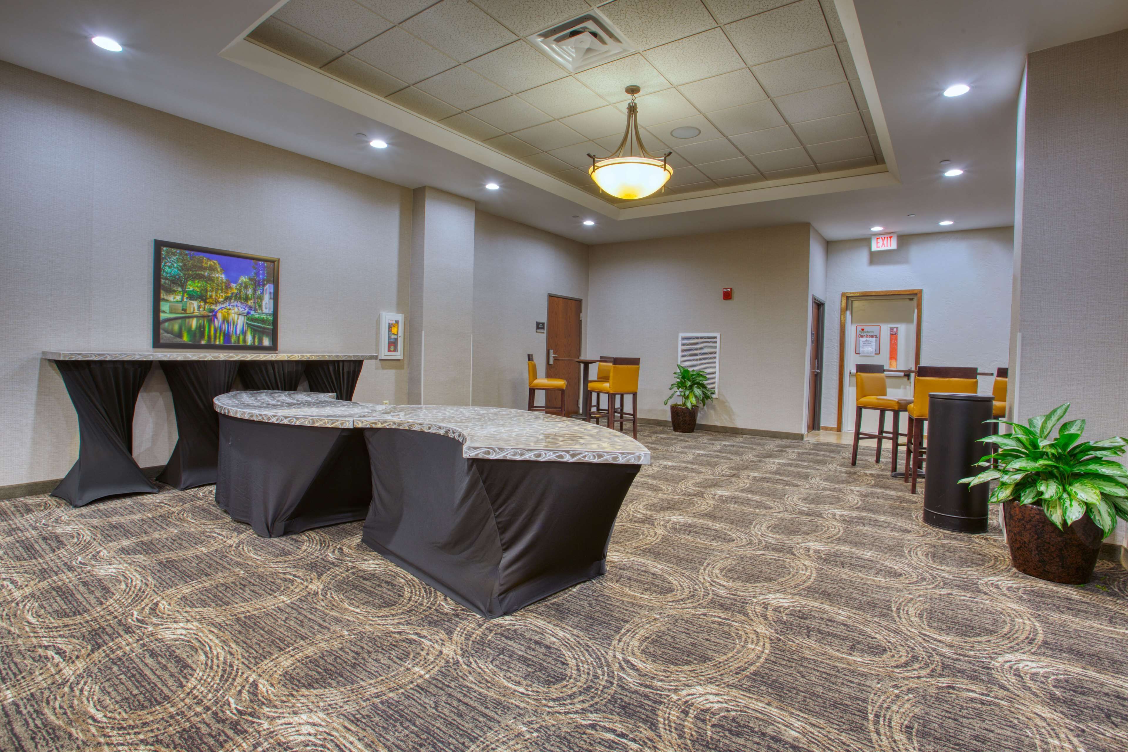 A conference room with a long table, chairs, and a carpeted floor.