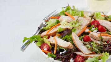 Ensalada con lechuga, tomates, zanahorias y lonchas de pollo.