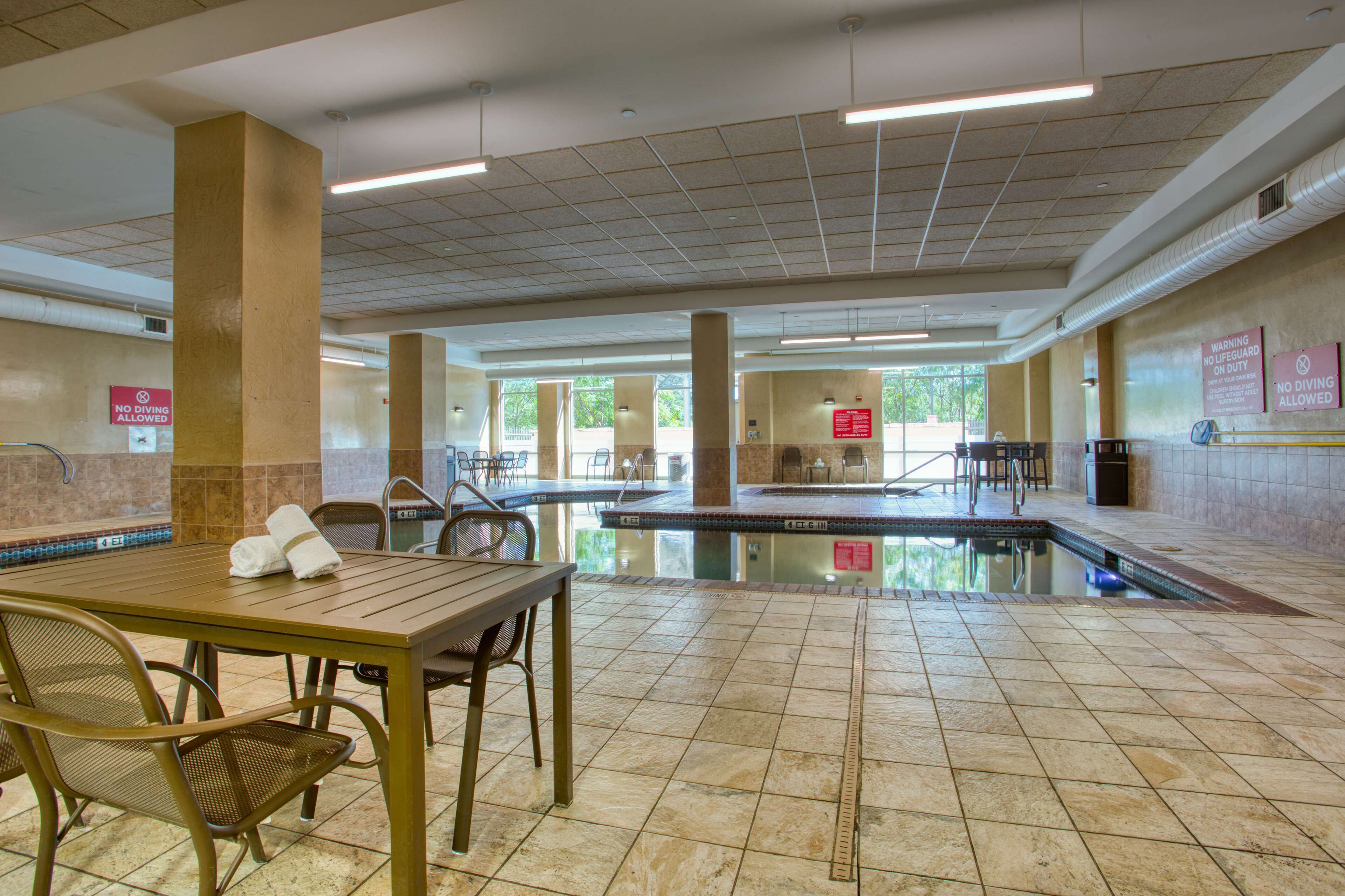 A pool area with a table and chairs, a lifeguard station, and a no diving allowed sign.