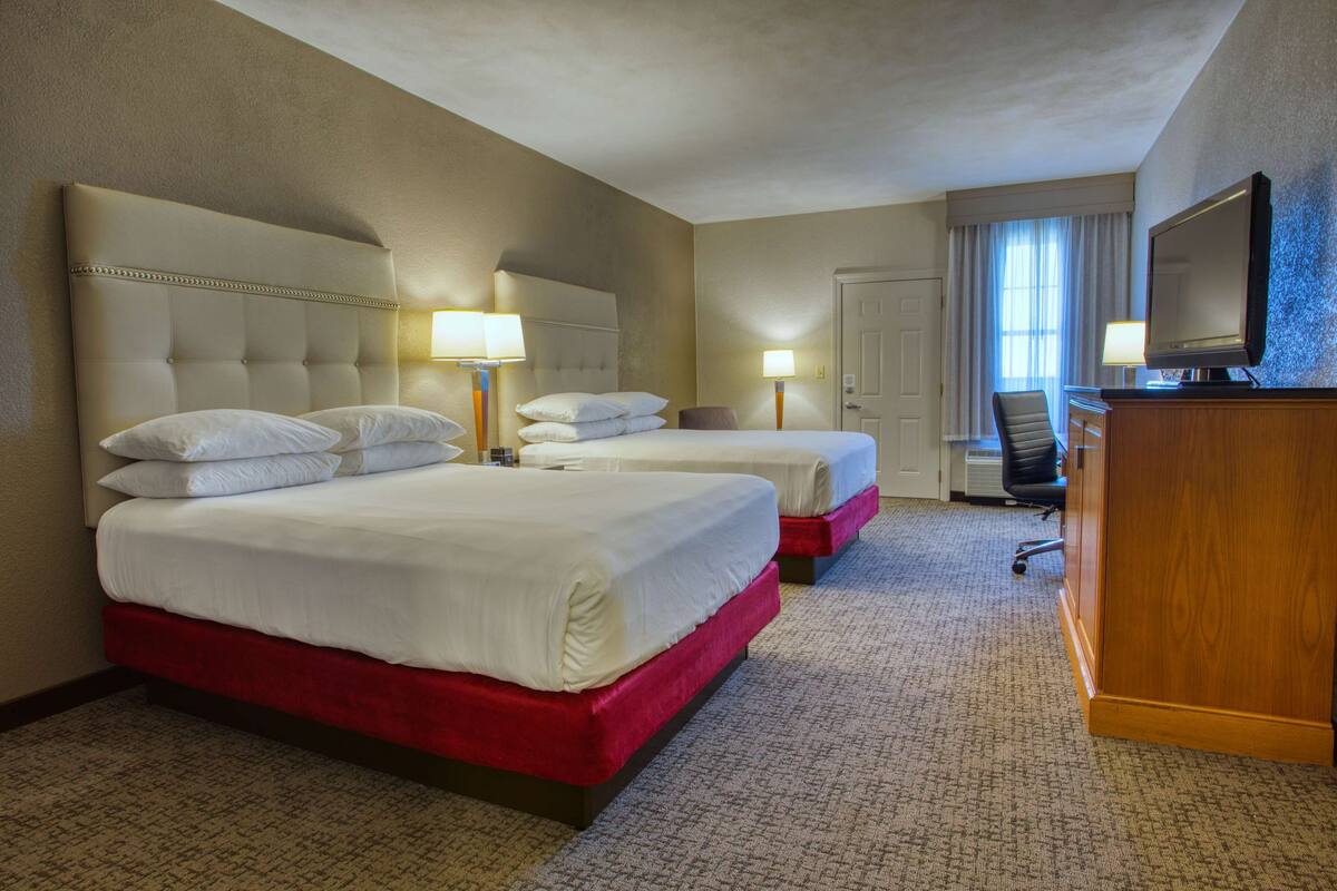 Une chambre d’hôtel avec deux lits, une télévision et un bureau.