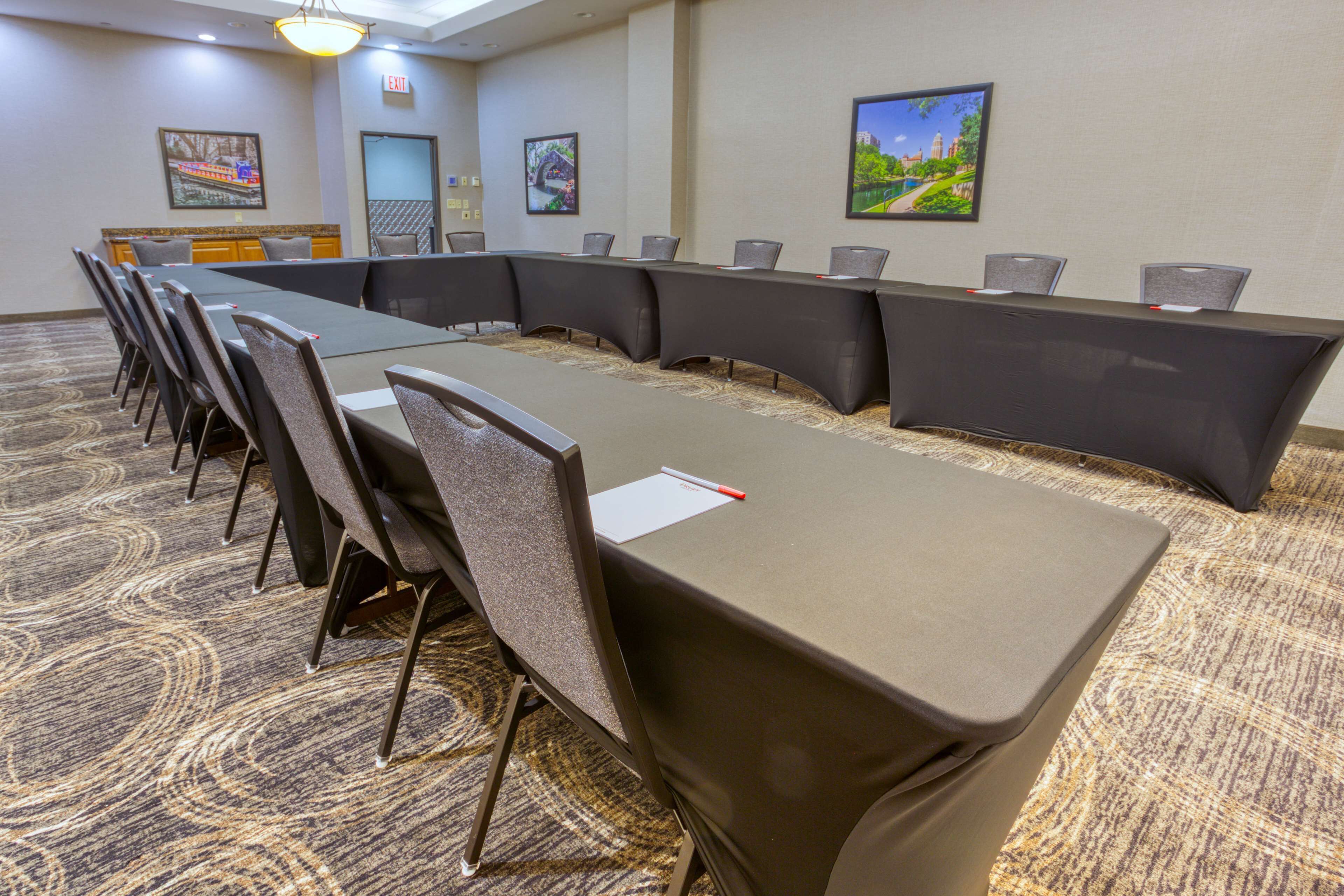 A conference room with a long table, chairs, and carpeted flooring.