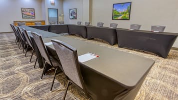 A conference room with a long table, chairs, and carpeted flooring.