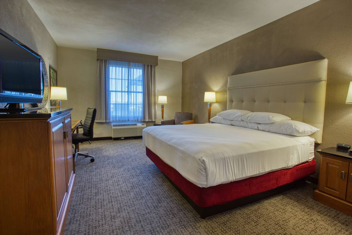 Une chambre d’hôtel avec un grand lit, une télévision, un bureau et une chaise.