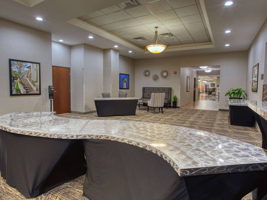 A hotel lobby with a curved reception desk, a seating area with a sofa and chairs, and a hallway leading to other rooms.