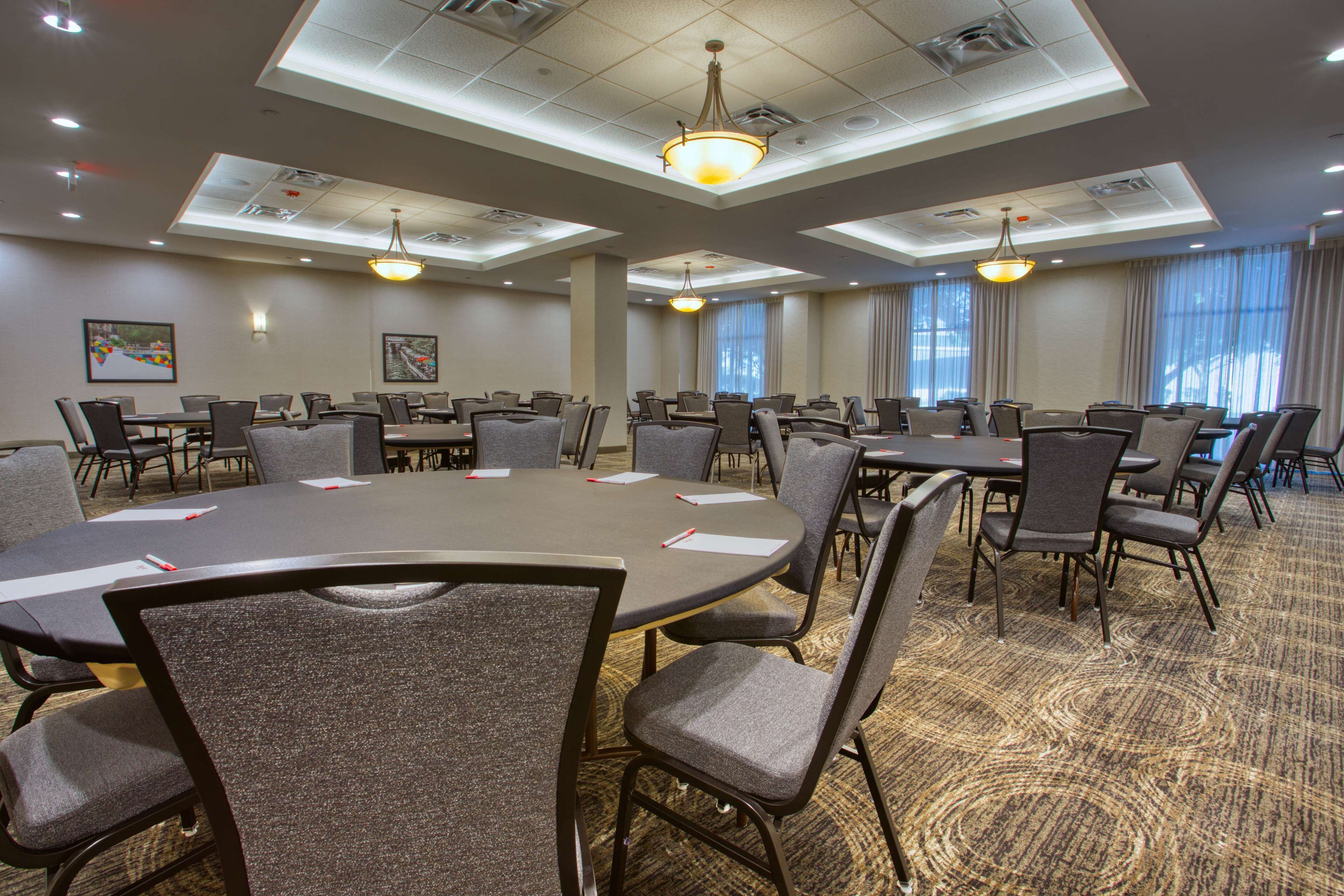 A conference room with a large oval table surrounded by chairs, recessed lighting, and a carpeted floor.