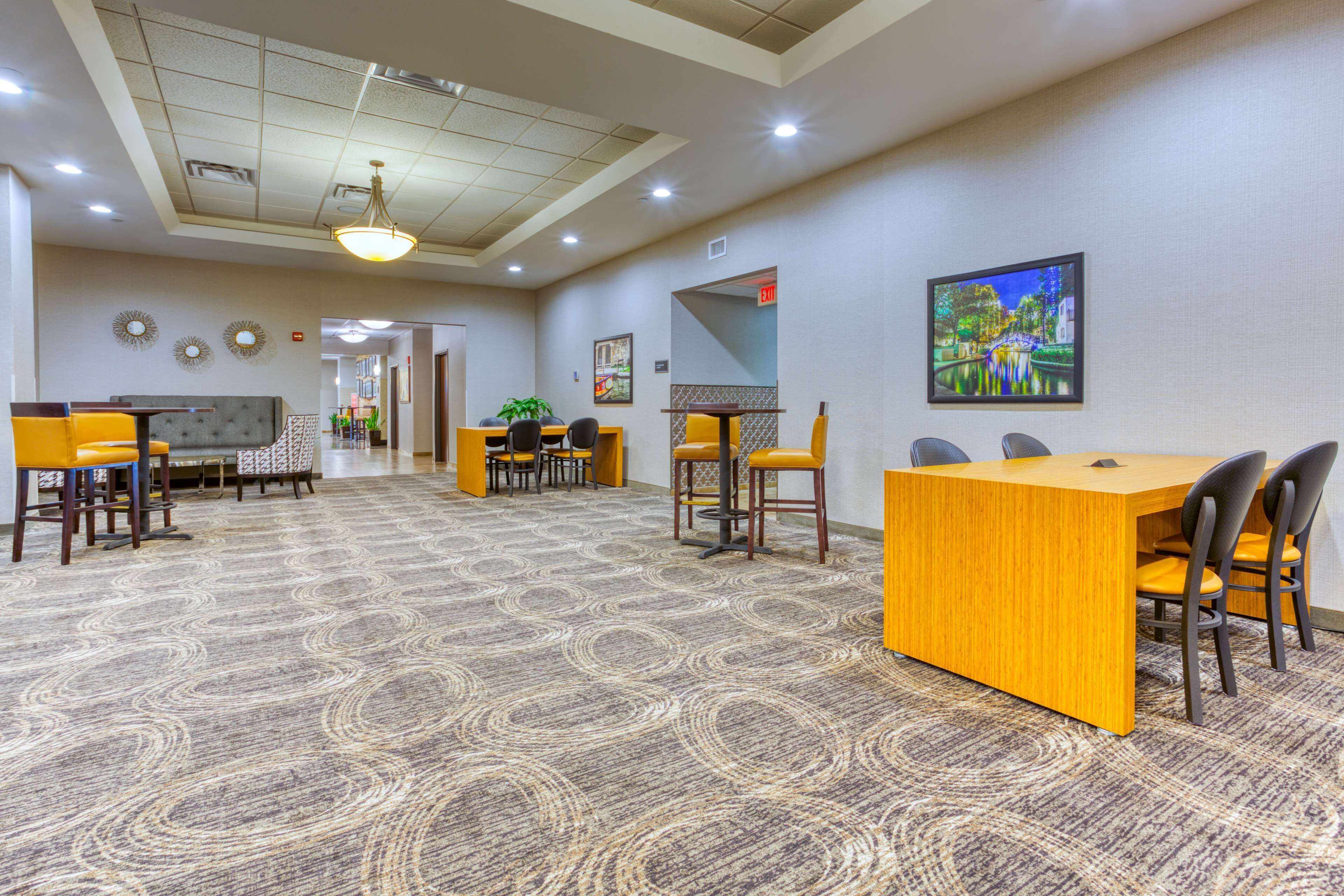 A hotel lobby with a reception desk, seating area, and a large carpeted floor.