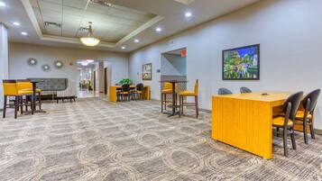 A hotel lobby with a reception desk, seating area, and a large carpeted floor.