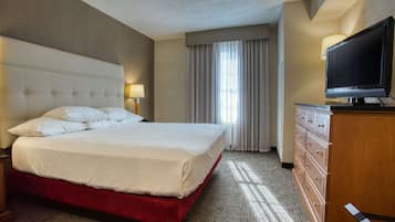 Habitación de hotel con una cama grande, televisor, cómoda y ventana con cortinas.
