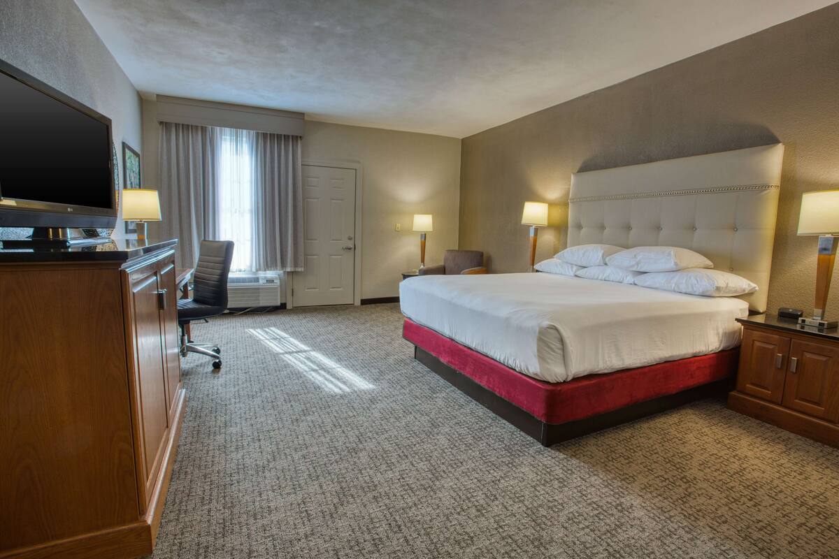 Une chambre d’hôtel avec un grand lit, un bureau avec une télévision et une chaise.