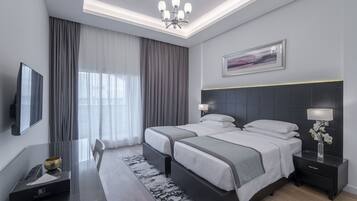 A modern hotel room with a large bed, bedside tables, a desk, and a flat-screen TV.