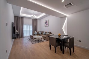 A modern living room with a sofa, coffee table, and dining table. - Rose Garden Hotel Apartments Barsha (Dubai)