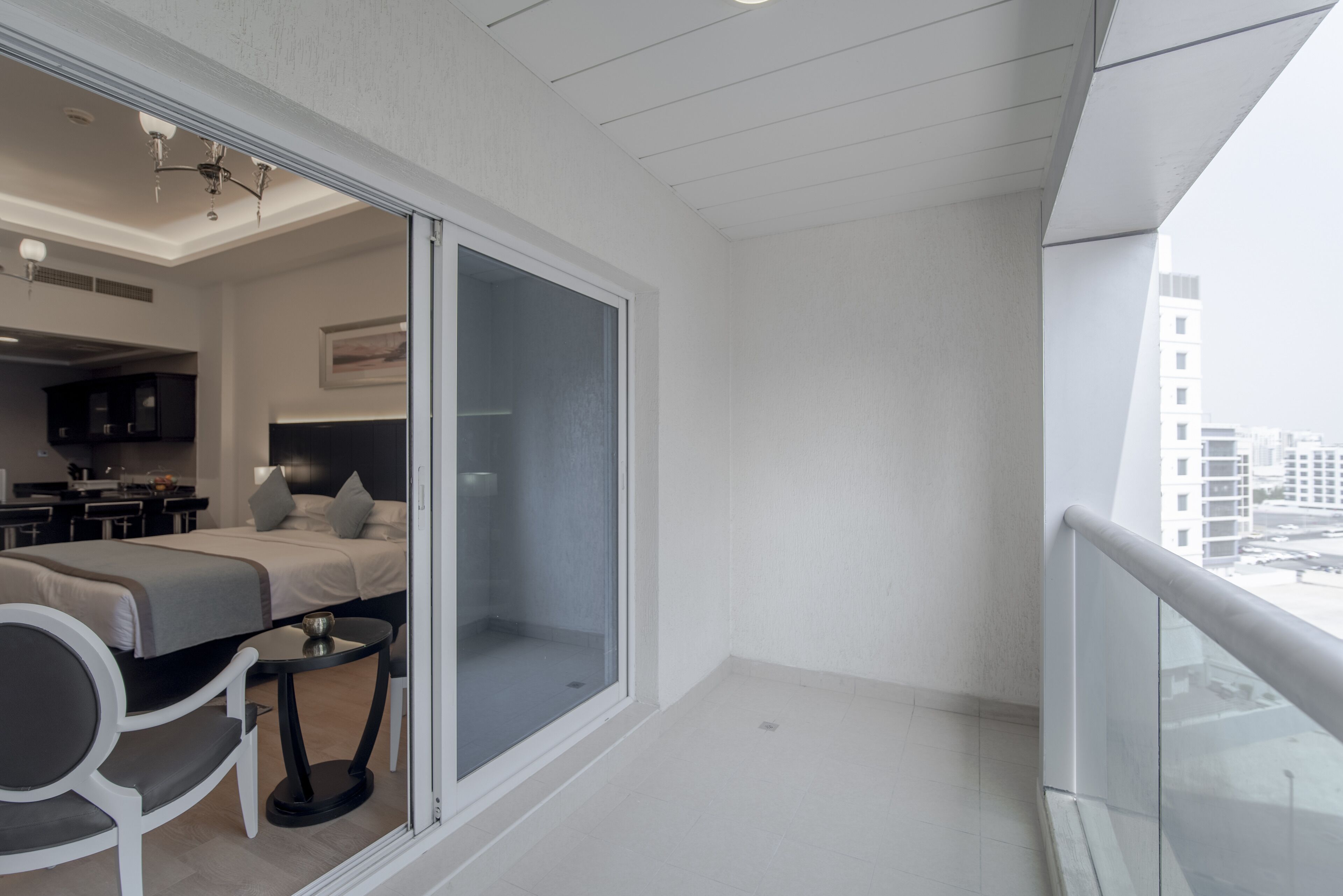 A modern hotel room with a balcony, a bed, a desk, and a chair.