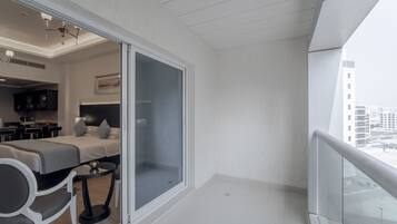 A modern hotel room with a balcony, a bed, a desk, and a chair.