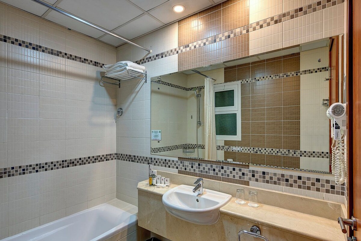 Ein Badezimmer mit einer Badewanne, einem Waschbecken und einem großen Spiegel.