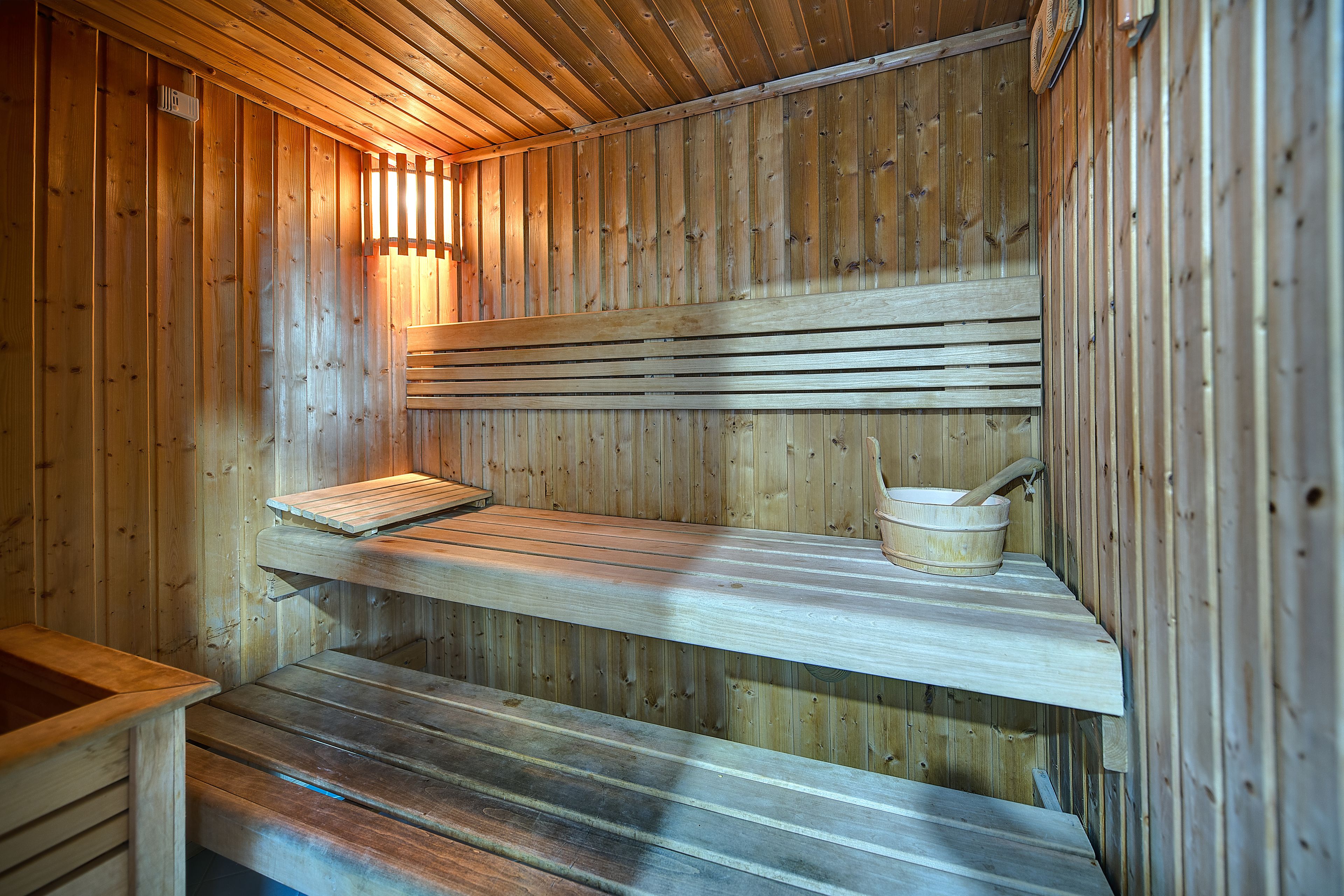 A wooden sauna with benches and a wooden basin.