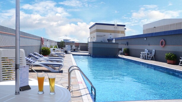 A pool area with lounge chairs, a table with drinks, and a menu sign.
