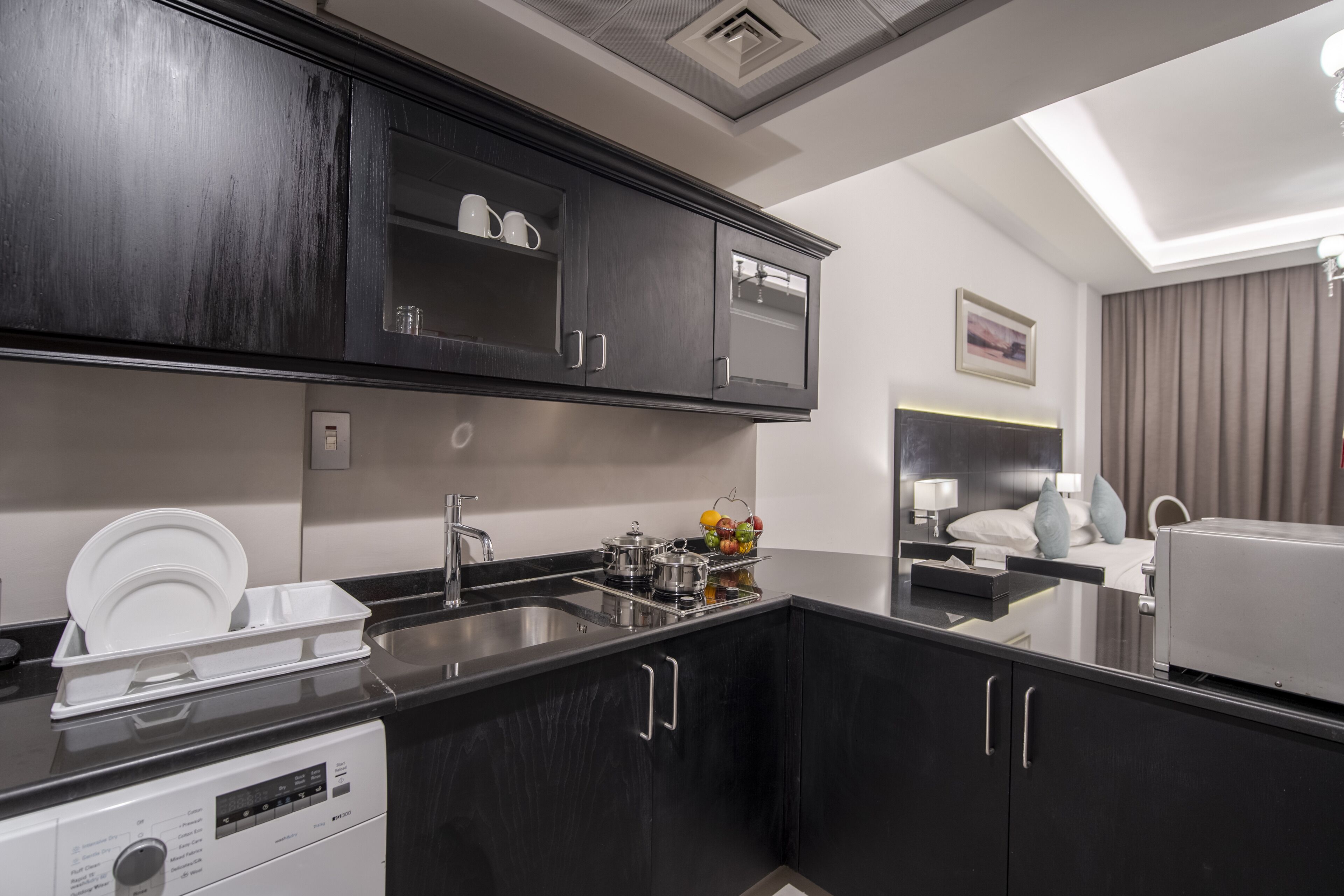 A modern kitchen with dark cabinetry, a stainless steel sink, and a built-in oven.