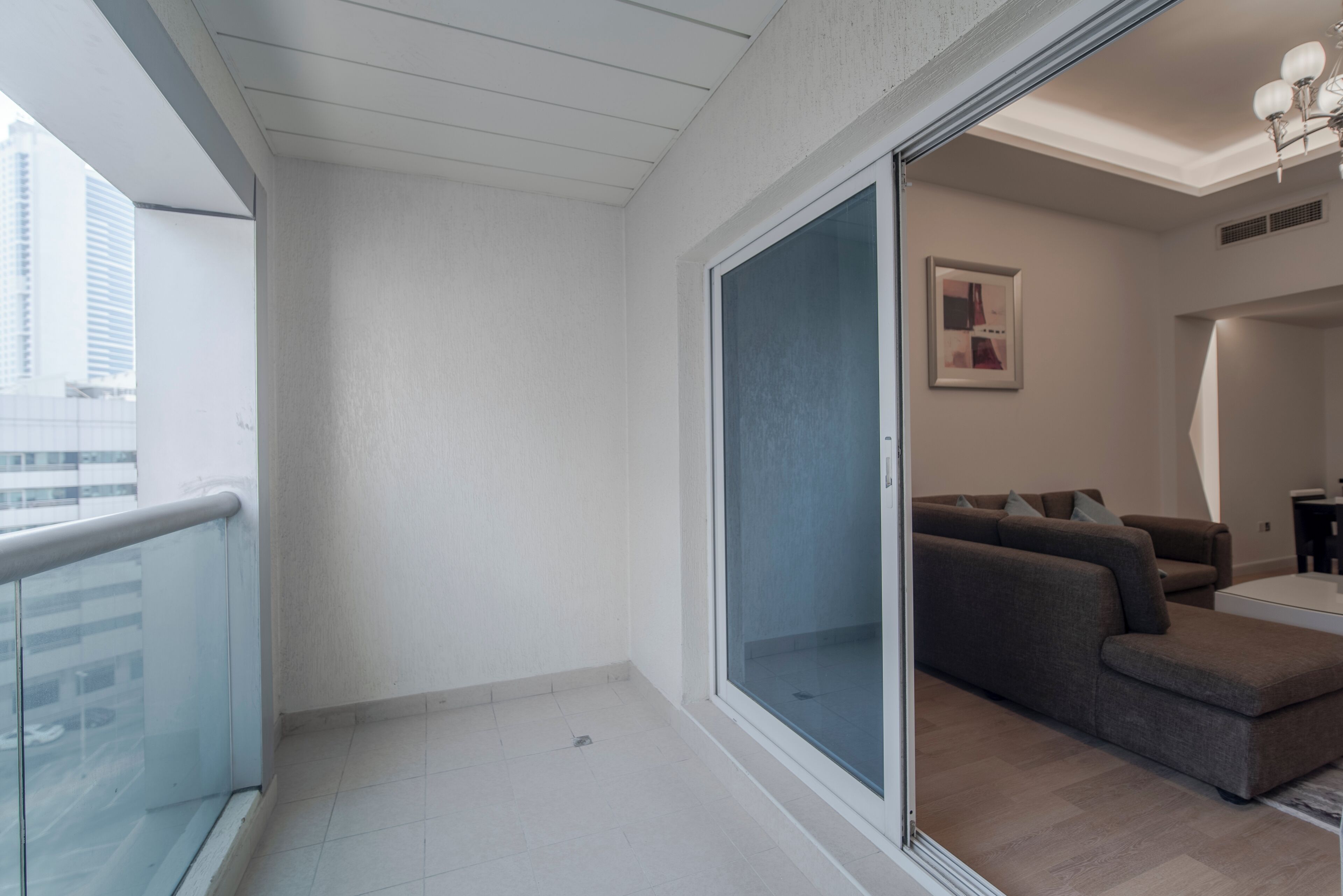 A balcony with a glass door leading to a living area with a sofa and a coffee table.
