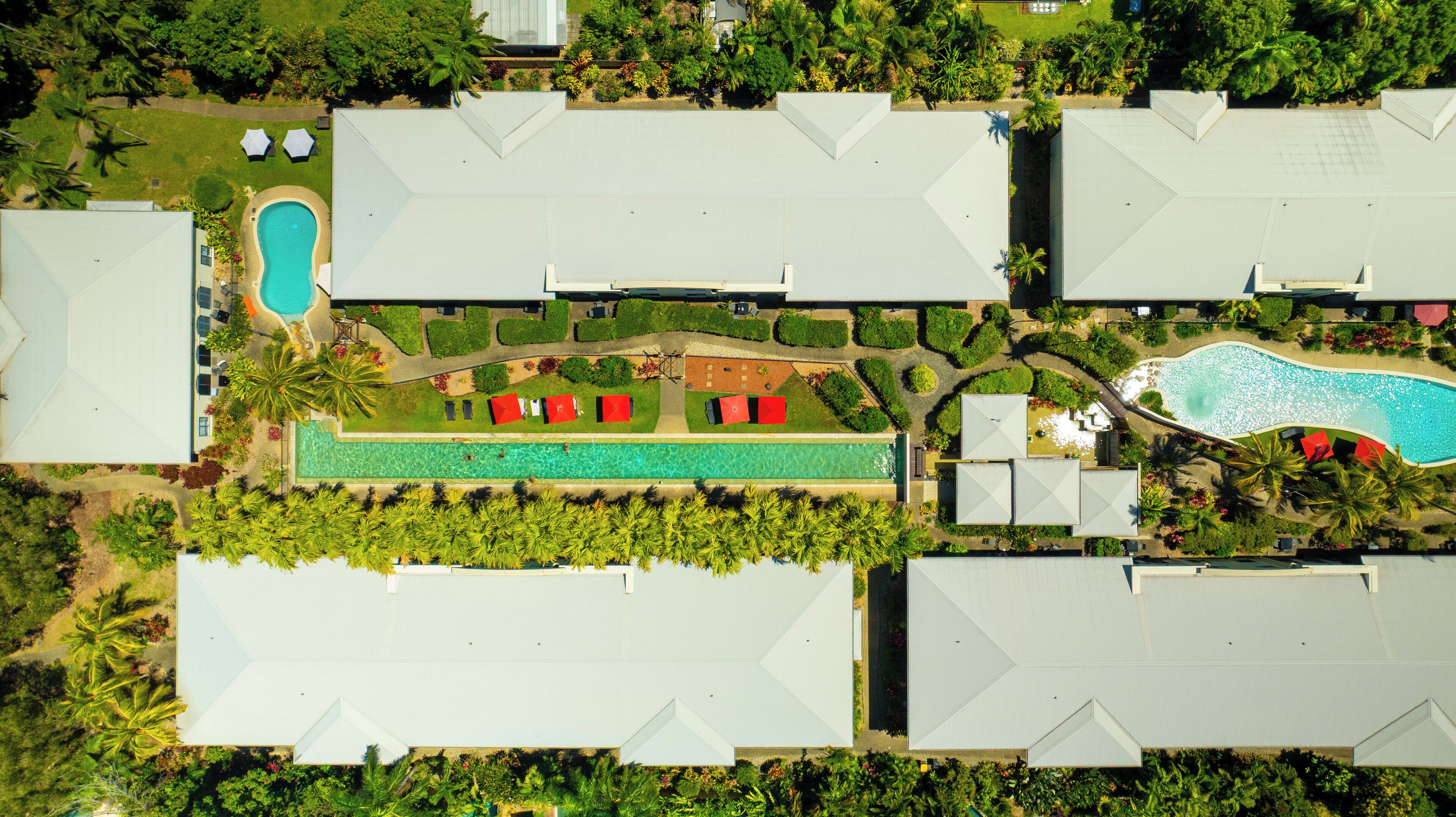An aerial view of a resort with multiple buildings, a swimming pool, and landscaped gardens.