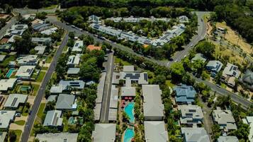 An aerial view of a residential area with houses, roads, and a central swimming pool.