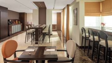 Un espace de restauration d’hôtel comprenant plusieurs tables et chaises, un coin cuisine et une vue sur la ville.