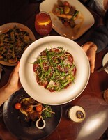 A dining table with various dishes, including a plate of pasta garnished with greens and cheese.