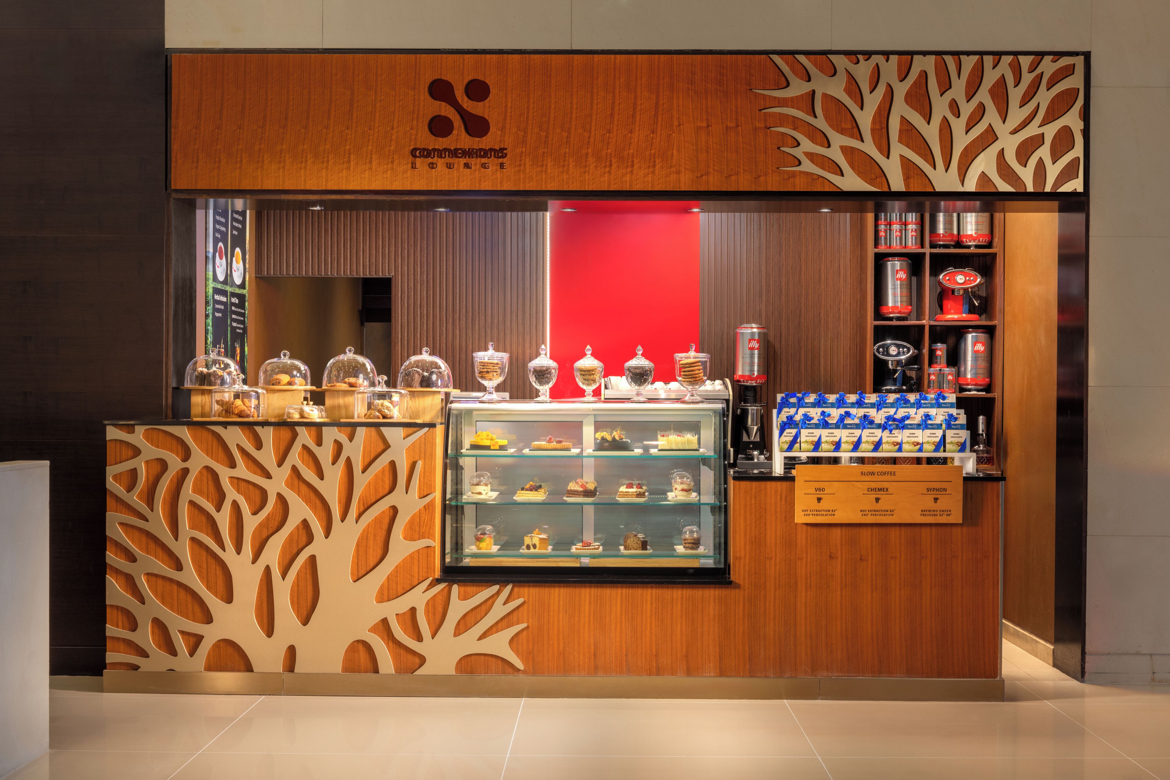 Un salon moderne avec une façade en bois, une vitrine réfrigérée où sont présentés des desserts et un espace dédié au café.