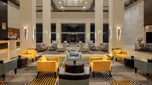 A lobby with a chandelier, seating areas, and a reception desk. - Radisson Blu Hotel, Dubai Barsha Heights (Dubai)