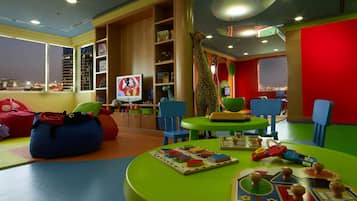 Children can play and relax in this vibrant playroom with a large TV, colorful furniture, and a giraffe-shaped chair.
