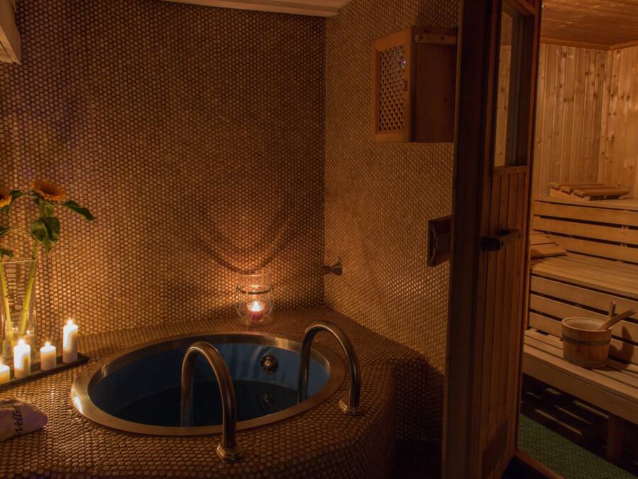Un sauna avec un banc en bois, une petite table et une baignoire.