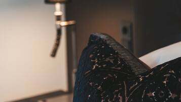 A bed with a dark patterned pillow and a bedside table with a lamp.