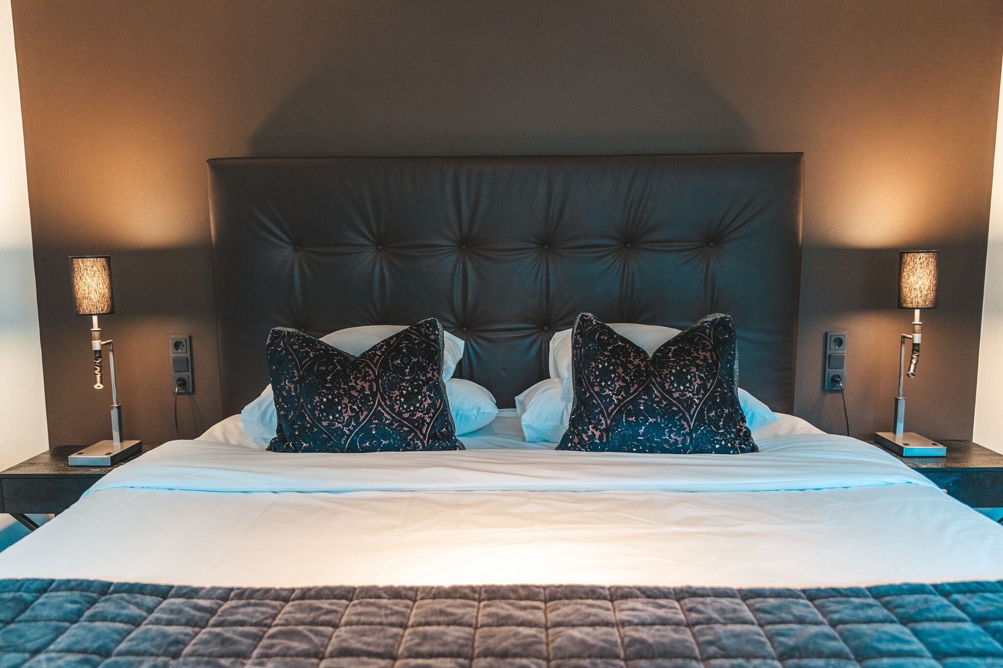 Une chambre d’hôtel avec un grand lit, deux tables de chevet et deux lampes.