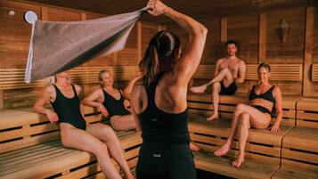 Una sauna con bancos de madera y una persona acomodando una toalla.