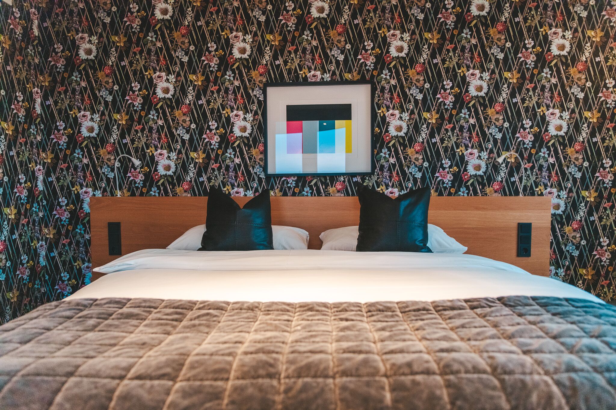 Una cama con cubrecama acolchado, cabecera de madera y dos almohadas.