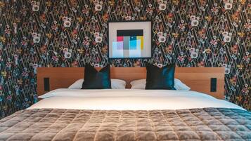 Una cama con cubrecama acolchado, cabecera de madera y dos almohadas.