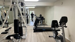 Un gimnasio con equipo cardiovascular, máquinas de pesas y espejos.