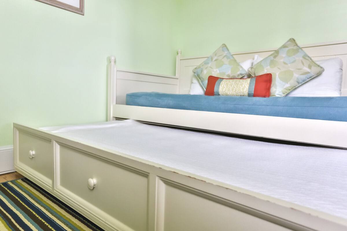 Ein Bett mit weißem Gestell, einer blauen Matratze und Zierkissen.