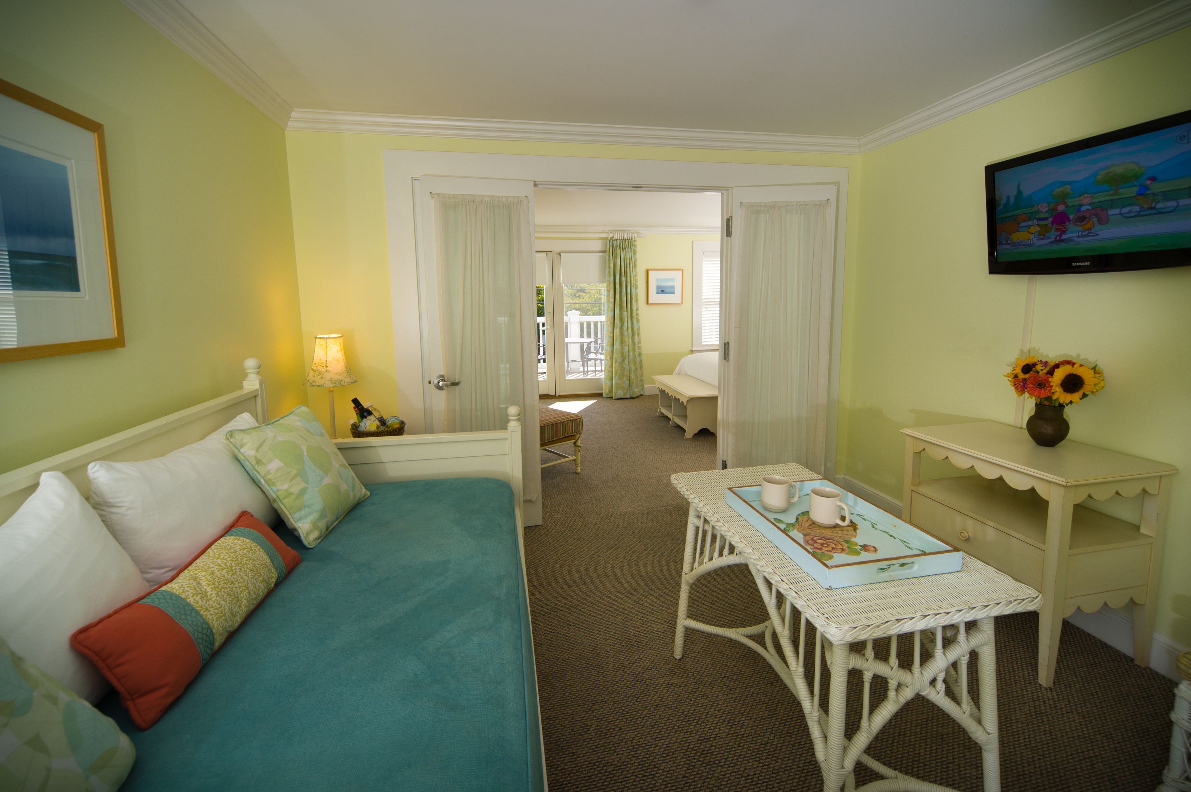 A hotel room with a bed, a small table with a tray, a television, and a view of the balcony.