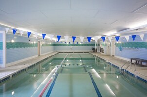 Piscina interior com pistas demarcadas, piso azulejado e parede com padrão de ondas.