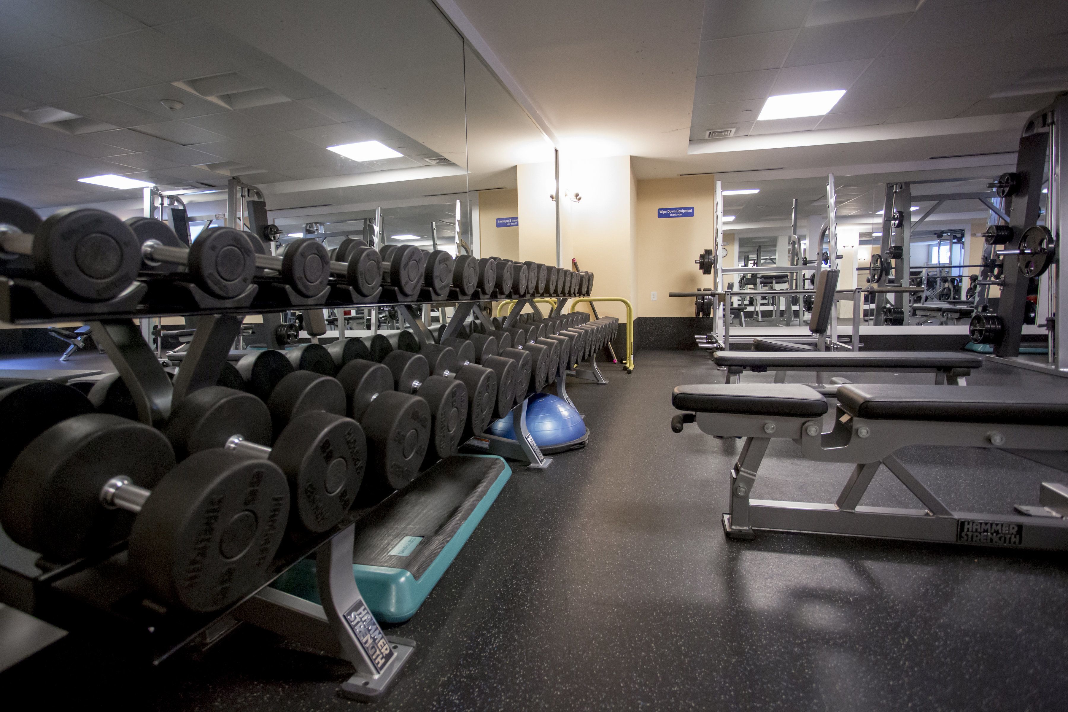 Een sportschool met gewichthefapparatuur, trainingsmachines en spiegels.