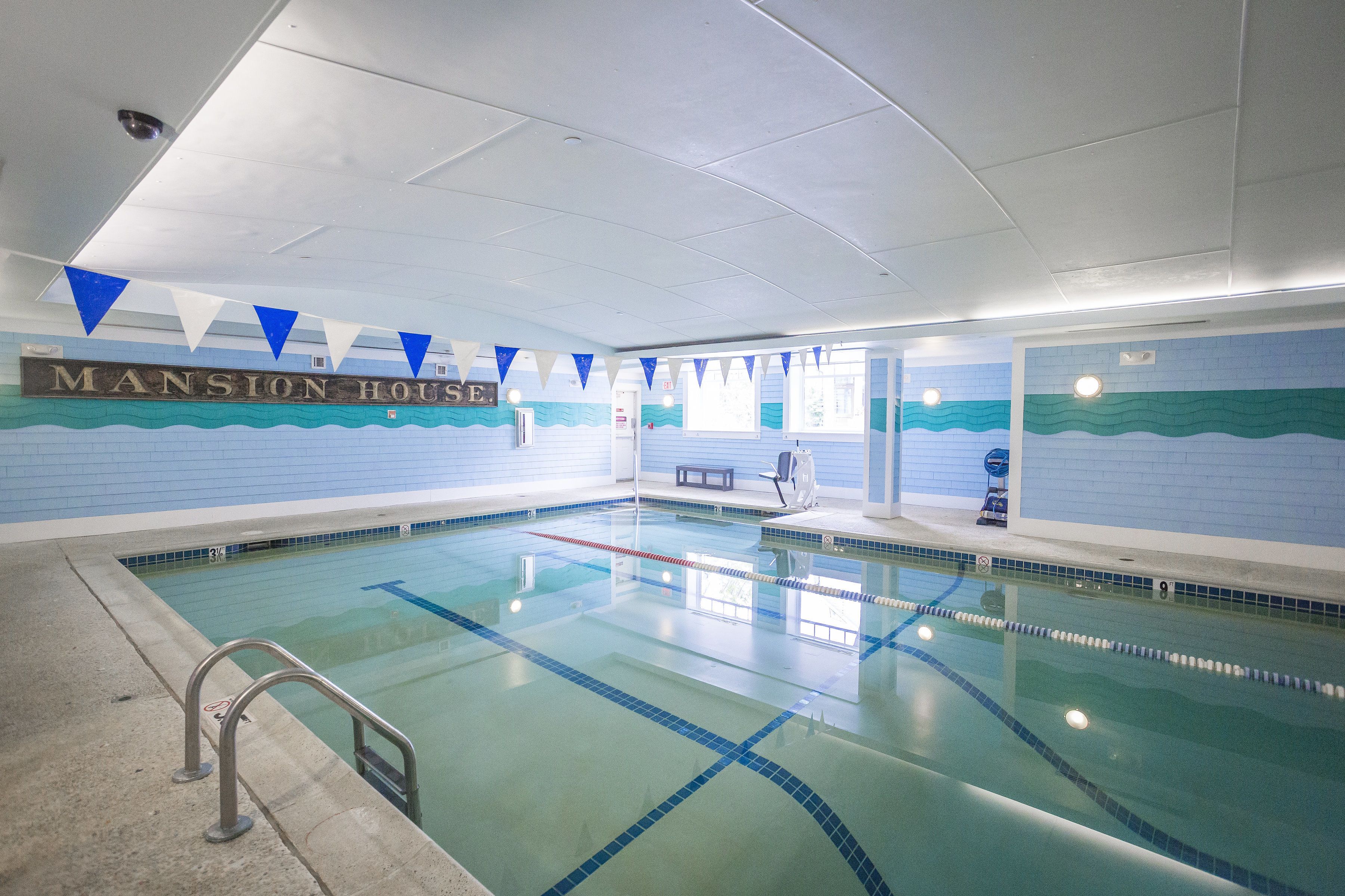 Una piscina con separadores de carril, un banco y un cartel que dice "Mansion House".