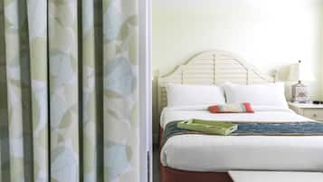 Een netjes opgemaakt bed met witte lakens en een groene dienblad, een houten hoofdbord en een nachtkastje met een lamp.