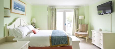 A hotel room with a bed, a desk, a chair, a dresser, a television, and a window with curtains.