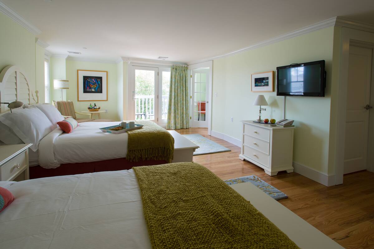 Ein Hotelzimmer mit zwei Betten, einem Fernseher, einem Schreibtisch mit Lampe und Blick ins Freie.