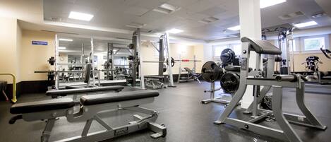 A gym with various exercise equipment, including a bench press, squat rack, and weight bench.