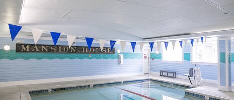 A swimming pool with lane dividers, a bench, and a wall with the text "MANSION HOUSE".