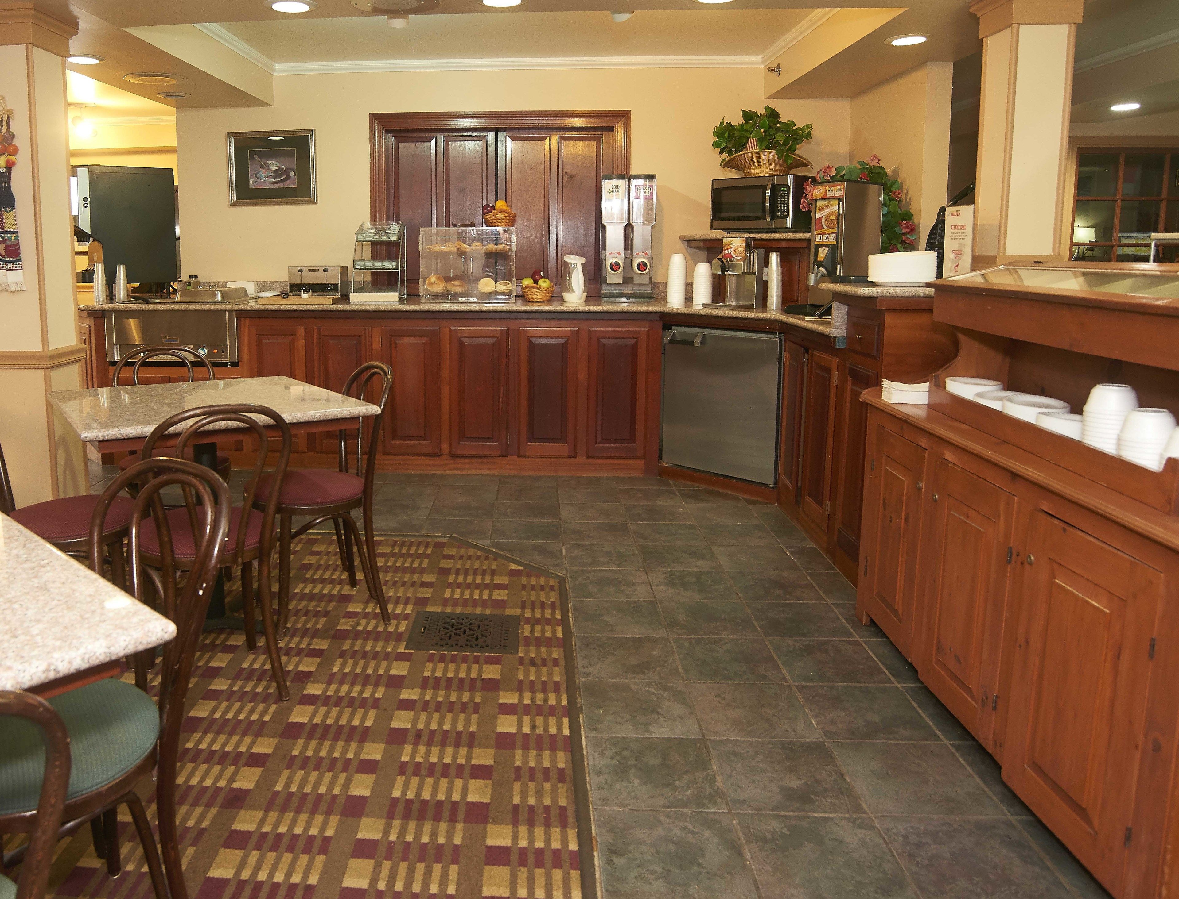 A kitchen with wooden cabinets, a microwave, a refrigerator, and a coffee maker.